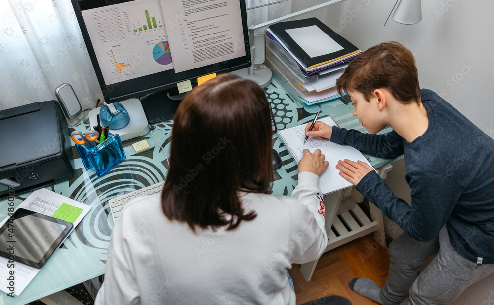 Mother helping her son with his homework while teleworking at home Mother helping her son with his homework while teleworking at home