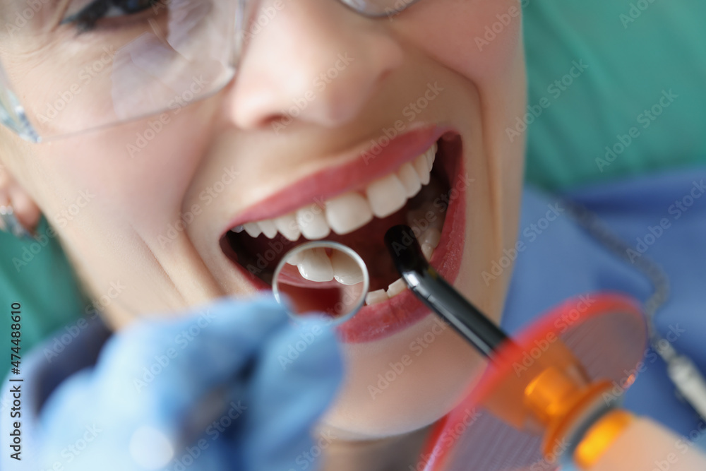 Female client on appointment in stomatology cabinet getting whitening procedure Female client on appointment in stomatology cabinet getting whitening procedure