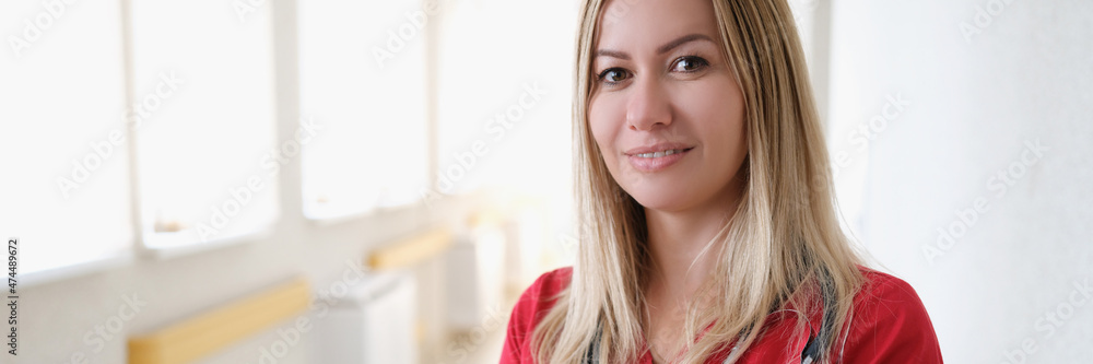 Portrait of young female doctor with stethoscope in red uniform in hospital corridor Portrait of young female doctor with stethoscope in red uniform in hospital corridor