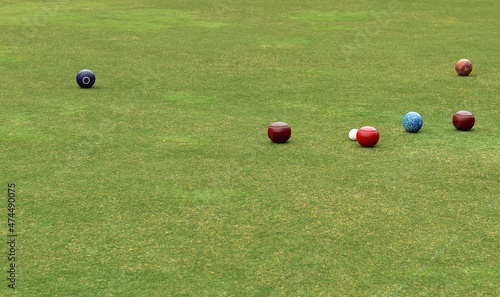 Some colored lawn bowls spread out around the white ball known as the jack