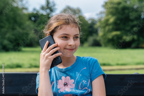 Wallpaper Mural Smiling teenage girl, making phone calls, sitting in a park. Torontodigital.ca