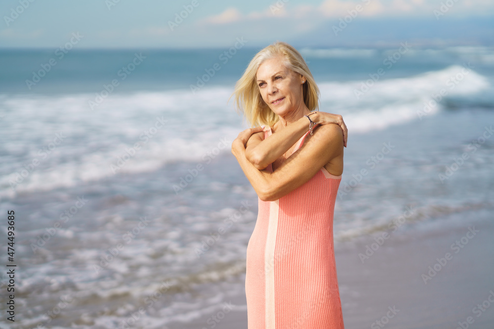 Older woman enjoying her free time looking at the sea from the shore of the beach. Older woman enjoying her free time looking at the sea from the shore of the beach.