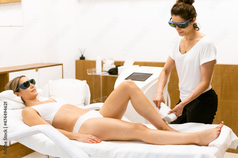 Woman receiving legs laser hair removal at a beauty center.
