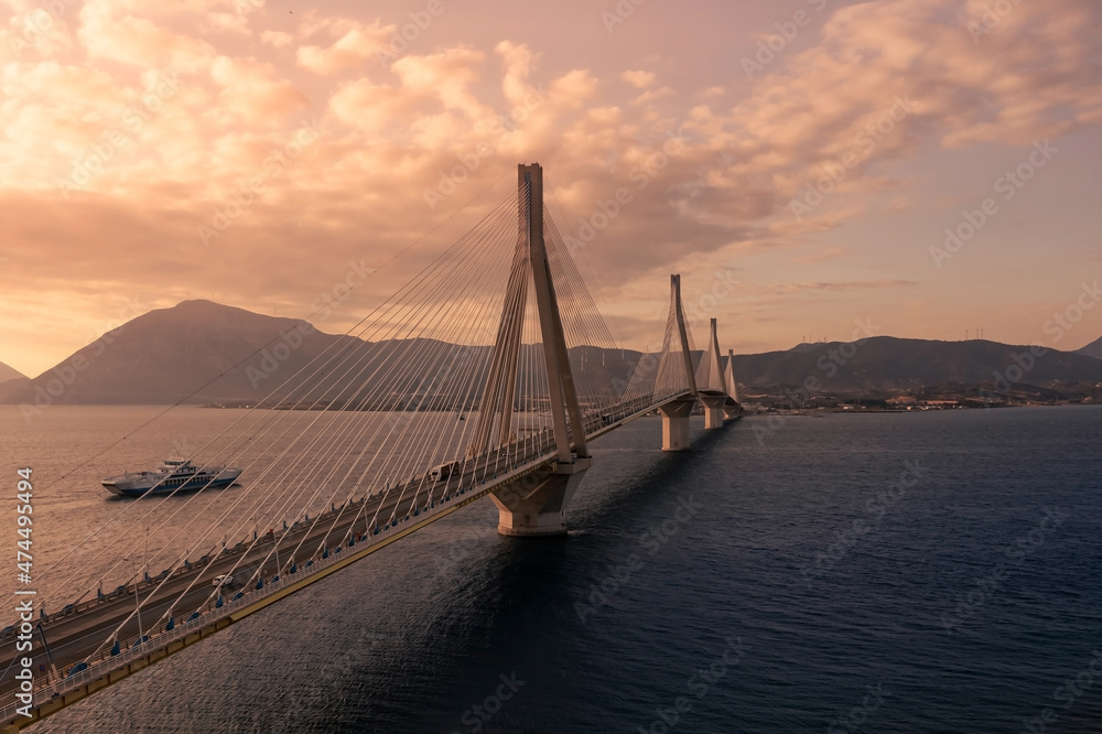 Obraz premium Huge suspension bridge with four large pillars over the sea strait at sunset, Peloponnese, Greece