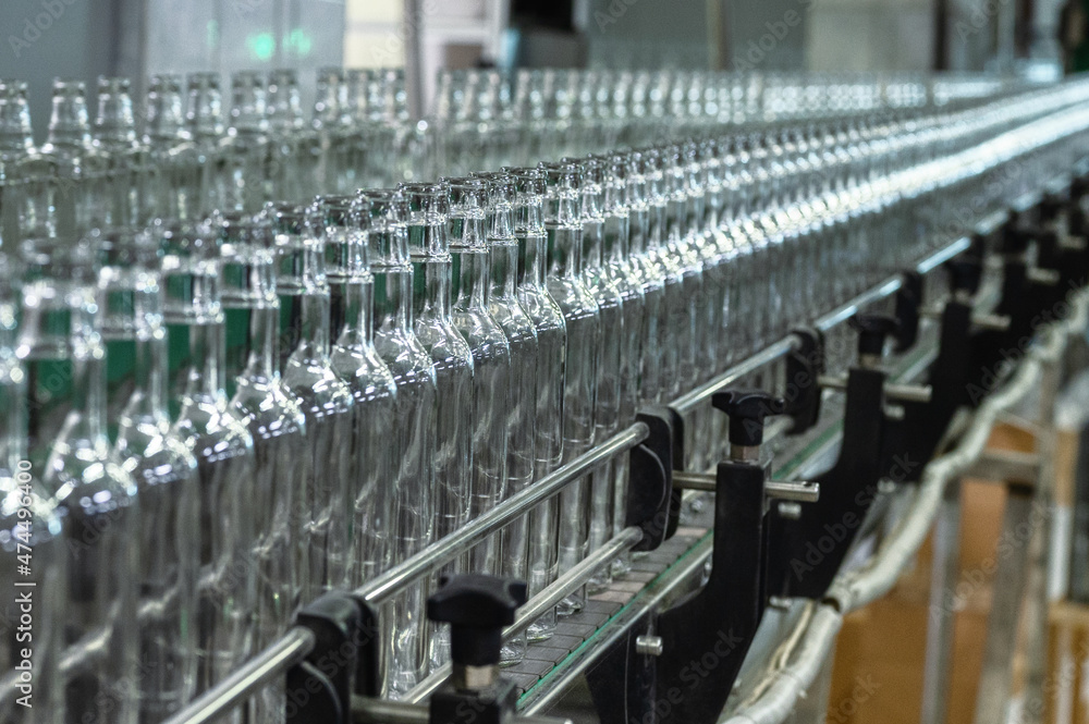 Fototapeta premium Conveyor with line of bottles for alcohol drinks in shop
