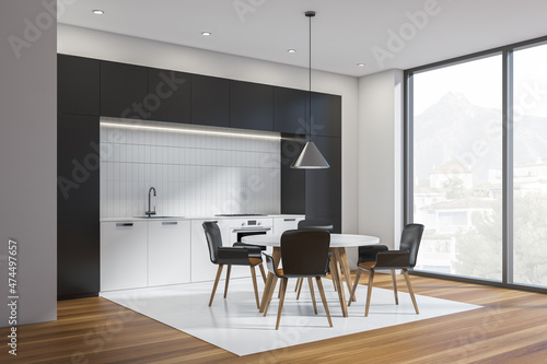 Black and white kitchen interior with table and chairs, wooden floor and window