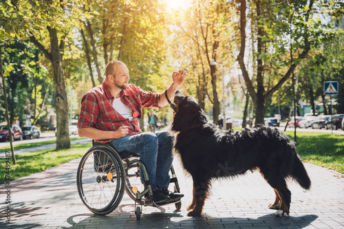 Happy young man with a physical disability in a wheelchair with his dog. © romaset