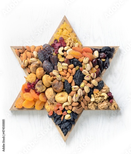 Mix of dried fruits and nuts - symbols of judaic holiday Tu Bishvat. Star of David . White wood texture background .