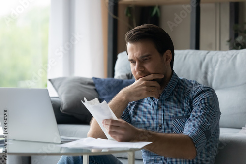 Man holds heap of checks for payment feels stressed due lack of money finances to pay, having debt looks disappointed. Individual entrepreneur experiences financial problem, crisis, bankruptcy concept photo