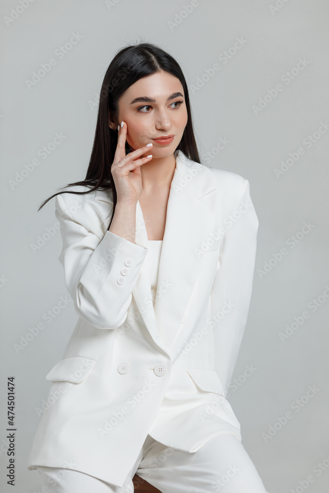 Beautiful brunette model wearing white business suit smiling with hand near her head Beautiful brunette model wearing white business suit smiling with hand near her head
