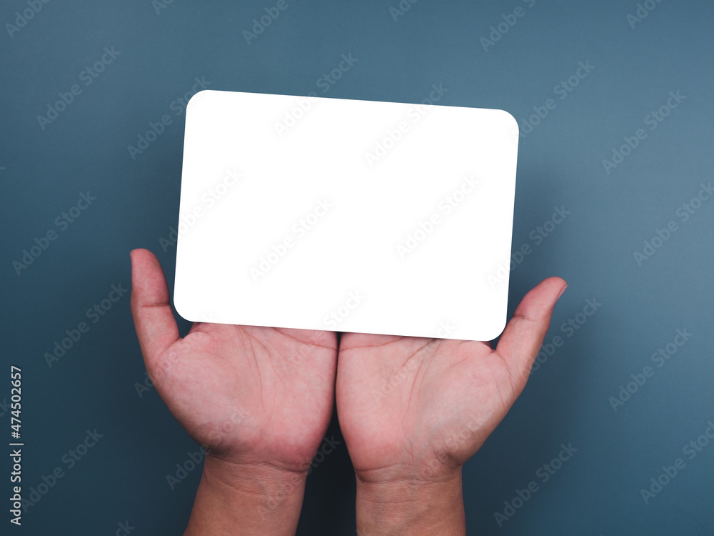 Mockup paper holding with two hands. Hands hold the white blank mock-up white paper with a rounded corner and a vertical style on a blue background. Mockup paper holding with two hands. Hands hold the white blank mock-up white paper with a rounded corner and a vertical style on a blue background.