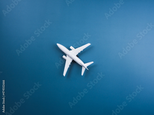 White plane toy model at the center on blue background, top view, minimal style. White airplane, flat lay design. Flight, travel concept.