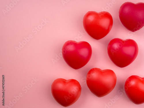 Group of red heart ball on pink pastel background with copy space. Concept of love, care, sharing, giving, well-being, and donation concepts, minimal style.