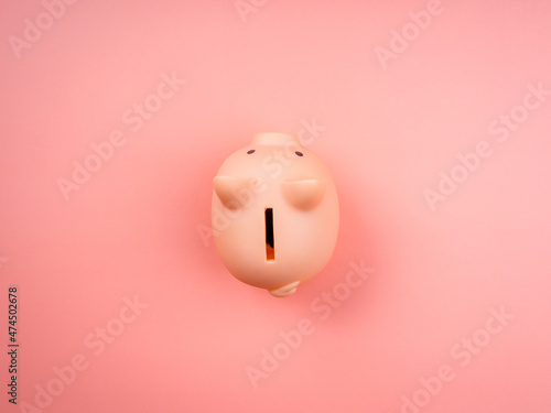 Pink piggy bank isolated on pink pastel background, top view, minimal style. Saving money and business investment concept.