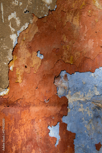 Multi-colored layers of rust and light blue peeling paint on stonework and walls of old buildings.