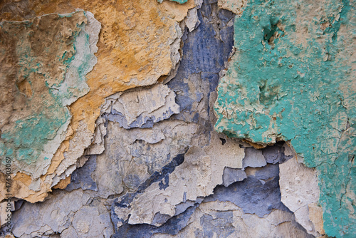 Multi-colored layers of cracked and peeling paint on stonework and walls of old buildings.