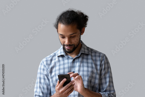 African man use smartphone pose on grey studio background, chatting in social media network, buying goods services through web store ecommerce website. Modern tech, connection, new application concept