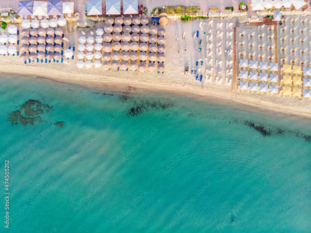 Aerial top view of sandy beach and turquoise sea, with umbrellas and sun loungers in Beautiful sunny summer day