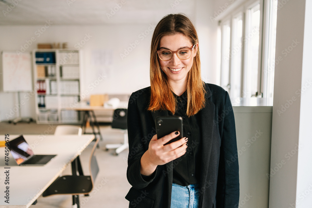 Young businsswoman smiling as she reads a phone message Young businsswoman smiling as she reads a phone message