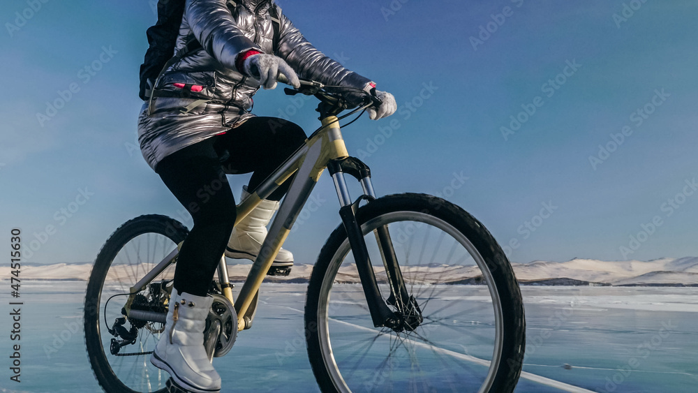 Obraz premium Woman is riding bicycle on the ice. Tires on bike are covered wi