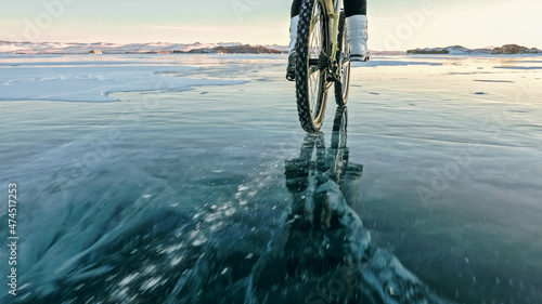 Woman is riding bicycle on the ice. Tires on bike are covered wi