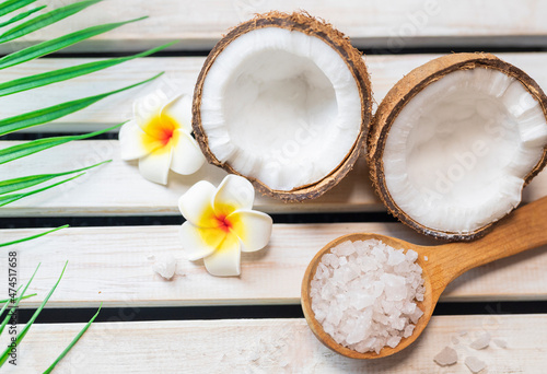 sea ​​salt in a wooden spoon with coconut for beauty care and mango flowers