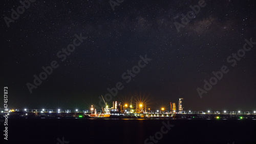 Oil ship tanker loading oil at the oil brige on the sea from refinery for transportation. at night over lighting and starlight background process