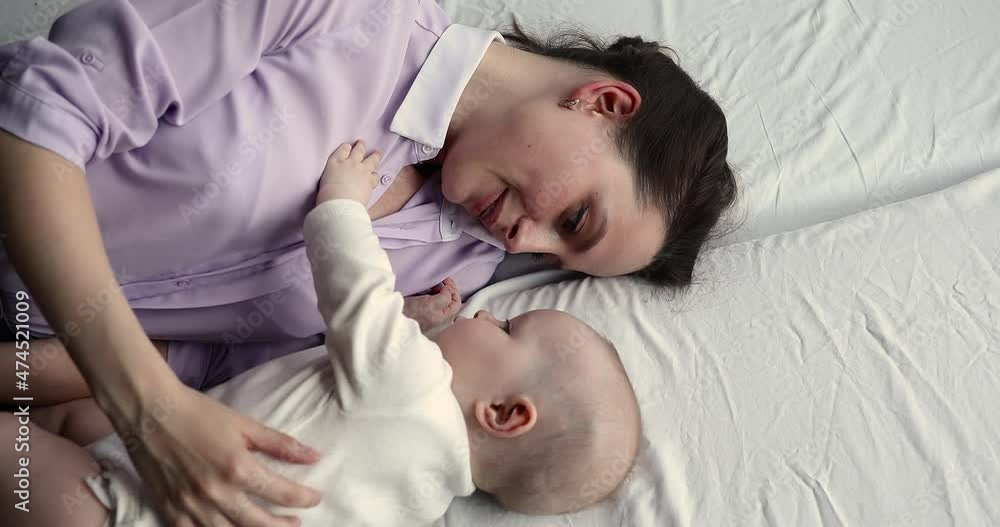 Tender embraces of love. Affectionate young female enjoy motherhood lie on bed hug cute little infant talk caress beloved babe feel bonding devotion. Mom and baby child cuddle on bed relax at morning Tender embraces of love. Affectionate young female enjoy motherhood lie on bed hug cute little infant talk caress beloved babe feel bonding devotion. Mom and baby child cuddle on bed relax at morning