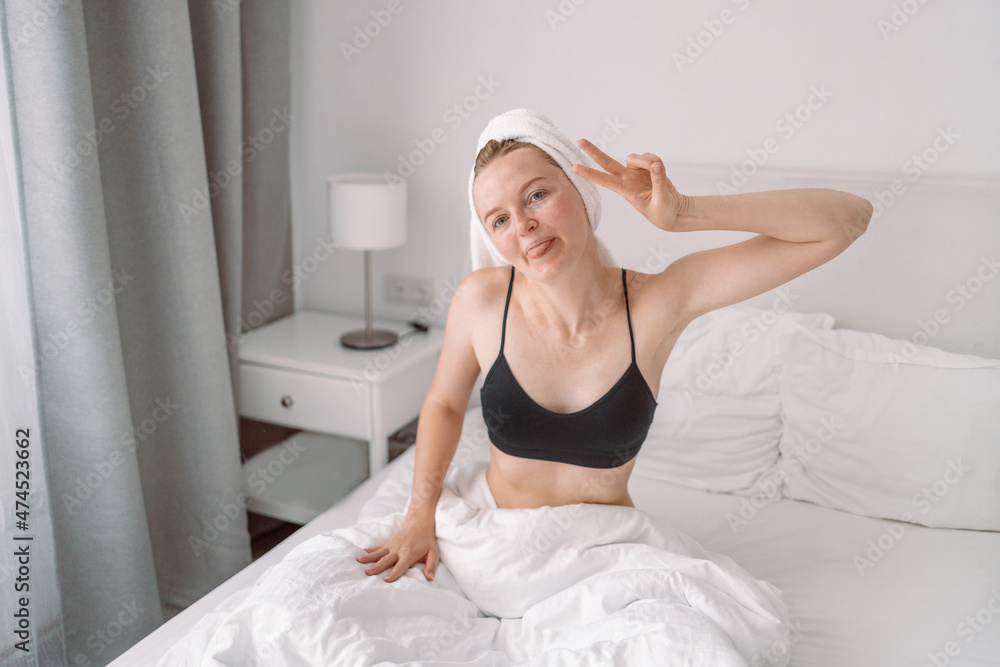 Positive attractive woman posing in a bedroom after waking up with sunrise morning, showing a peaceful gesture Positive attractive woman posing in a bedroom after waking up with sunrise morning, showing a peaceful gesture