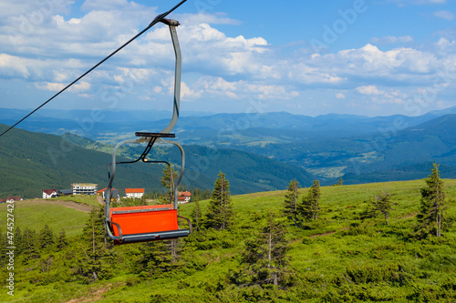 Mountain landscape with cable car and forest against cloudy blue sky. Travel and adventure concept.