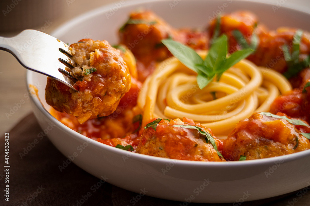 Close up meatballs with long Spaghetti in tomato sauce in a white plate on wooden table Close up meatballs with long Spaghetti in tomato sauce in a white plate on wooden table