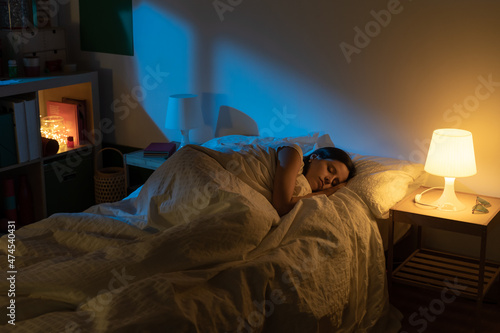 Fotografie Beautiful girl suffering from insomnia lying in her bed with Blue Colors from the moon