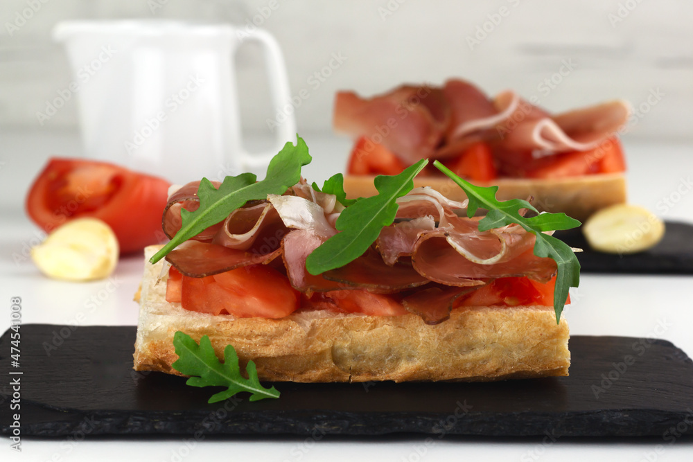 Spanish tapos with hamon, italian bruschetta with proscuitto on a black slate