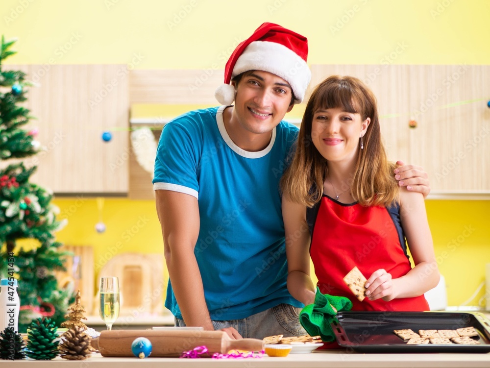 Young couple celebrating Christmas in kitchen Young couple celebrating Christmas in kitchen