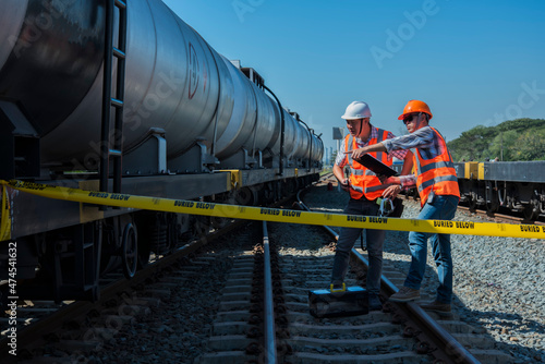two worker checking oil tank on yard. The engineer stand discussion work with laptop on rails. worker work on railway. construction  engineer  workers  rail  Infrastructure.