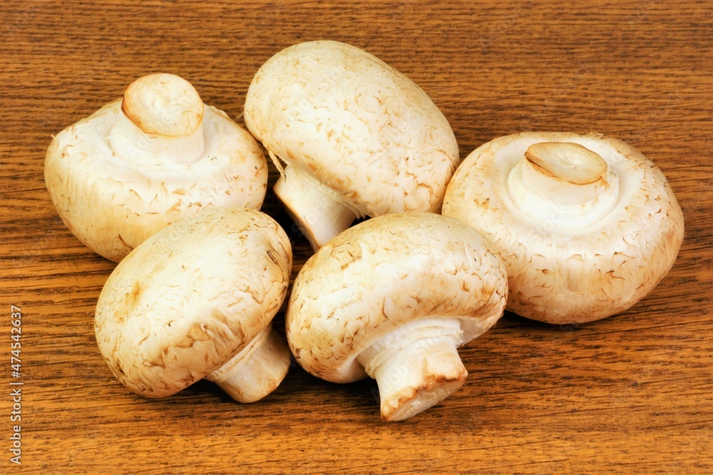 Mushrooms champignons, isolated on a wooden background. Popular healthy food in cooking. Mushrooms champignons, isolated on a wooden background. Popular healthy food in cooking.
