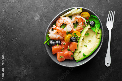 Salmon shrimp vegetables bowl. Blueberries, tomatoes, spinach, rice, seafood for a healthy diet. Top view