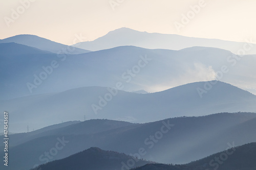 Blue silhouette of mountains on horizon, early misty morning.