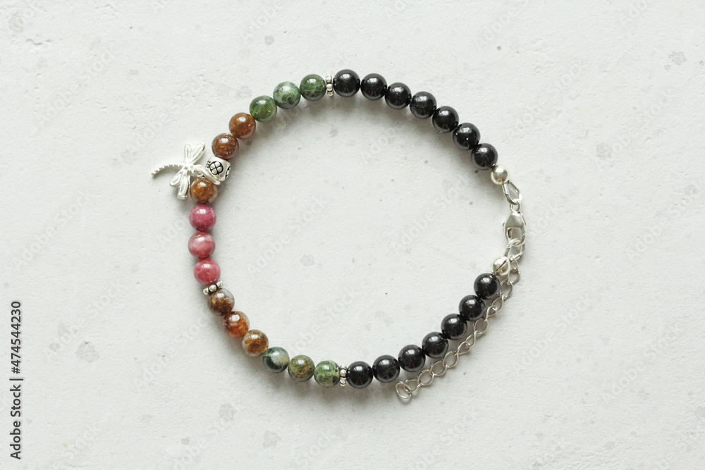 Tourmaline bracelet. Bracelet made of stones on hand from natural stone Tourmaline. Bracelet made of natural stones. Handmade jewelry. Handmade bracelets on light modern background. Pendant dragonfly Tourmaline bracelet. Bracelet made of stones on hand from natural stone Tourmaline. Bracelet made of natural stones. Handmade jewelry. Handmade bracelets on light modern background. Pendant dragonfly