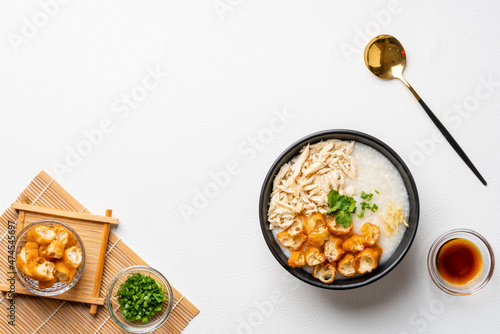 Traditional Chicken Porridge rice gruel in bowl shot on white background with negative space.