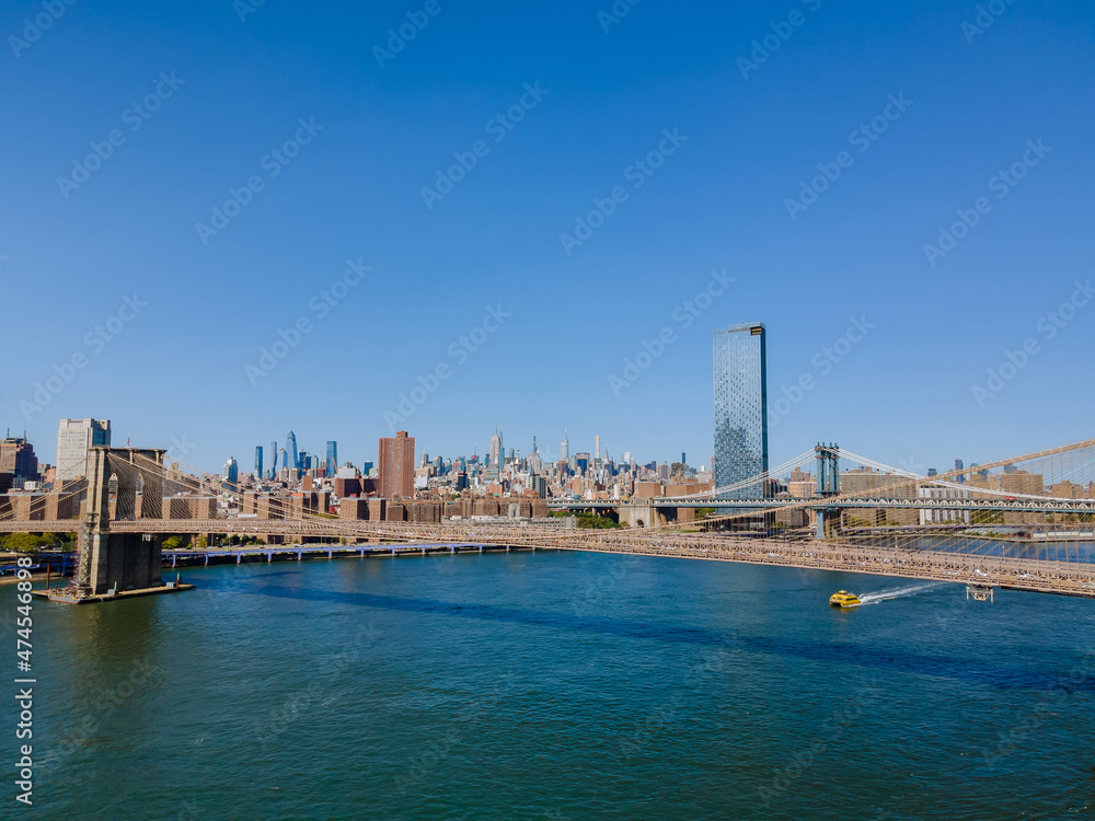Brooklyn and Manhattan Bridges with Manhattan New York City skyscrapers city over Hudson River.