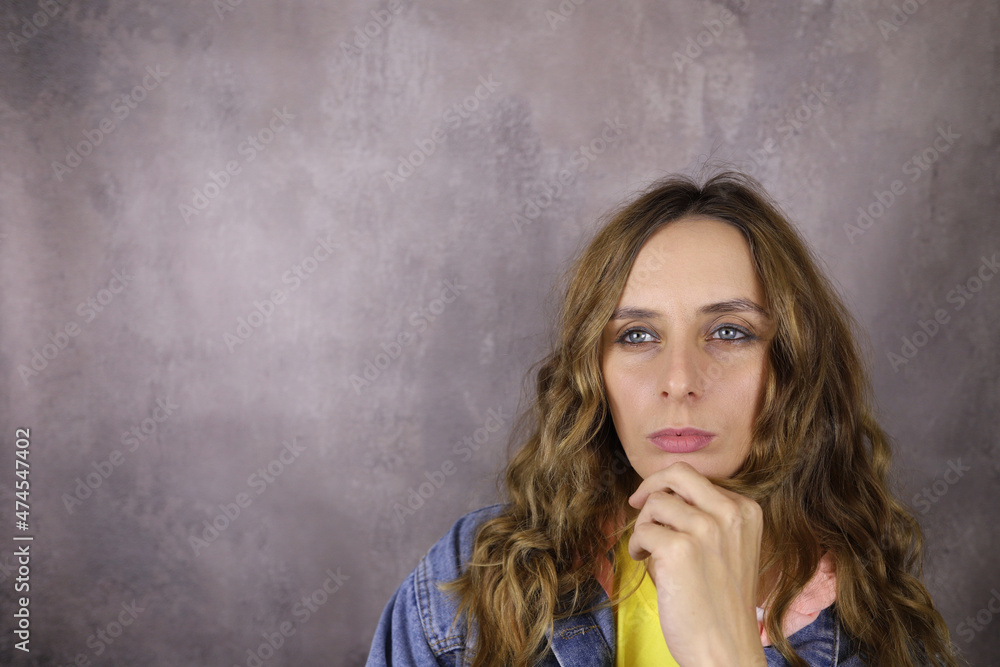 Fototapeta premium Portrait of a girl in casual clothes on a gray background. Copy space for text