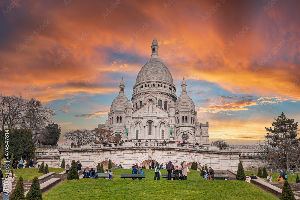 Fototapeta premium Magical sunset over Sacre Coeur cathedral with tourists and Parisians walking around. Beautiful sunset in Paris.