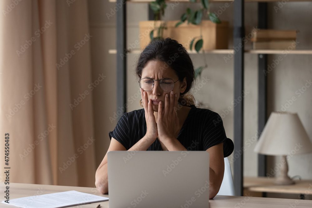 Sad young Hispanic woman look at screen work online on computer at home office feel unmotivated bored. Unhappy Latino female distressed with bad negative news or message on laptop on internet. Sad young Hispanic woman look at screen work online on computer at home office feel unmotivated bored. Unhappy Latino female distressed with bad negative news or message on laptop on internet.
