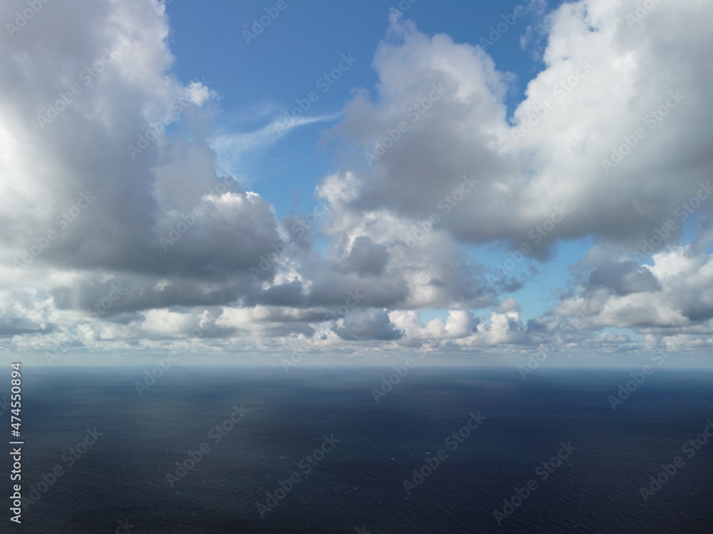 Abstract airy sky with moving plump clouds over the sea ocean. Small waves on clear water surface bokeh lights from sunrise. Holiday, vacation and recreational concept