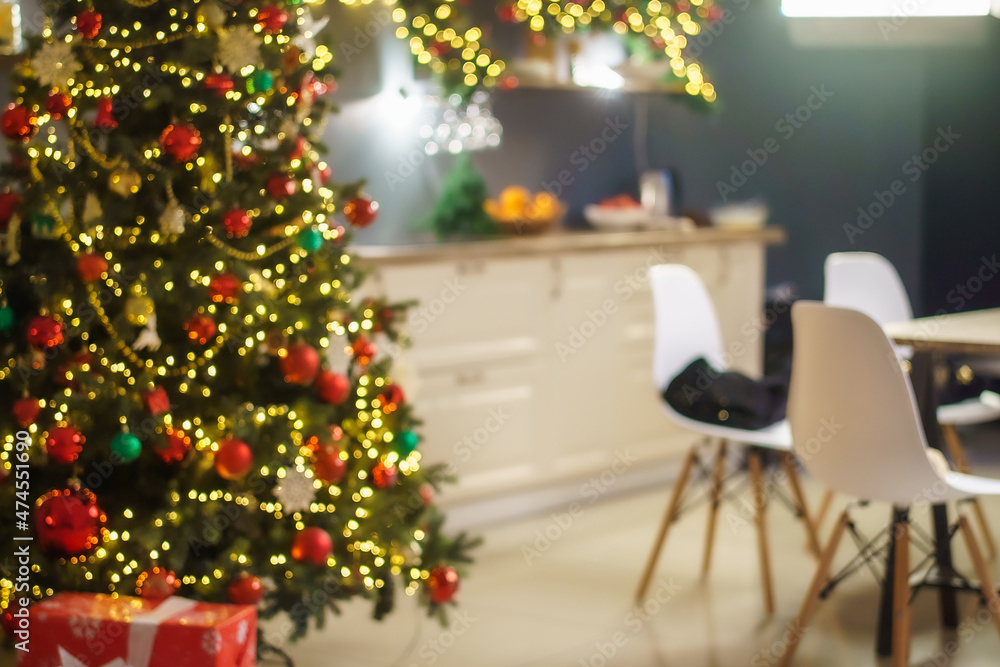 Christmas home room with Christmas tree and festive bokeh lighting, on background kitchen decorated for holiday . Christmas and new year interior-blurred background. Lots of lights that glow in dark.