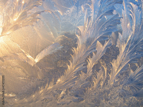 Ice pattern and sunlight closeup on window glass early in the morning