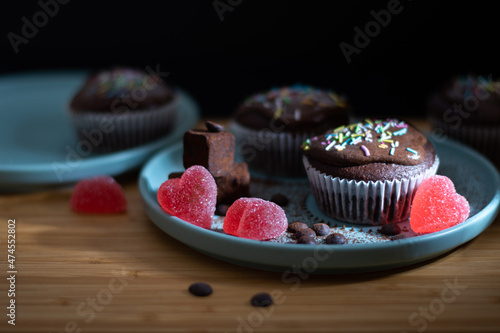 Delicious chocolate muffin cupcake with colourful sprinkles white cream topin, truffles and heart shaped candy for valentines day photo