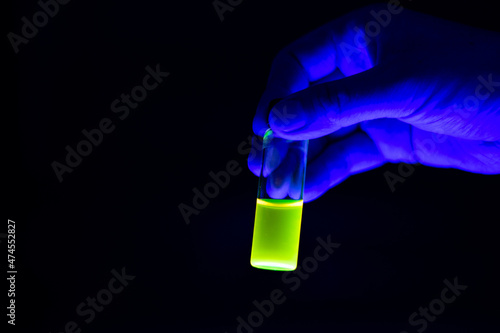 Canvas Print A scientist worker holding chemistry photochemical reaction green glass vials in a organic laboratory