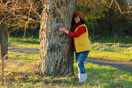 woman in the countryside relaxing outdoors, happy hugging a tree trunk in the Autumn, 
